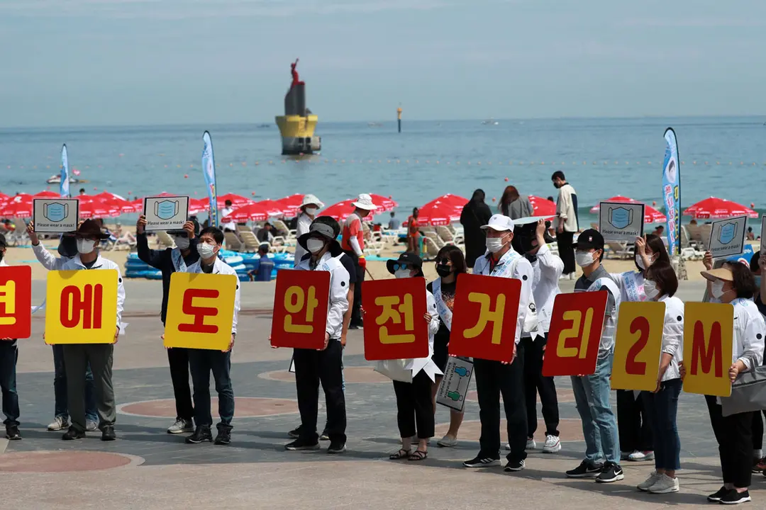 South Korea: Officials at the southeastern port city of Busan hold signs reminding visitors at Haeundae Beach to keep a 2-meter distance, to prevent the spread of the Corona virus. Photo: YNA/dpa.