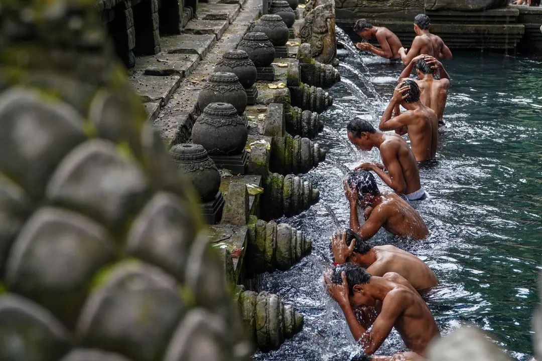 Indonesia. Men wash their bodies at the holy spring shower during the Banyu Pinaruh cleansing ceremony at Tirta Empul Temple. Photo: Dicky Bisinglasi/dpa