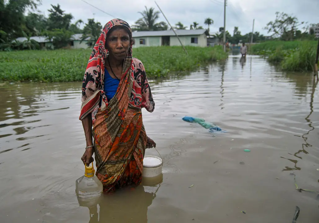 Bangladesh, Sylhet: A women walks in a flooded road after collecting drinking water through a flooded road at Sadarpur area following heavy rainfall triggered by monsoon over the last few days. Photo: Md Rafayat Haque Khan/dpa