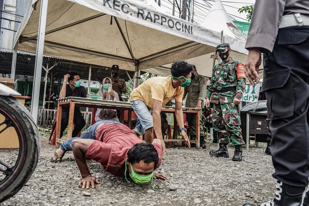Indonesia, Makassar: A motorist drops down and gives push ups in front of a member of the military as a punishment for entering the city of Makassar without carrying a COVID-19 free certificate. Photo: Herwin Bahar/ZUMA Wire/dpa