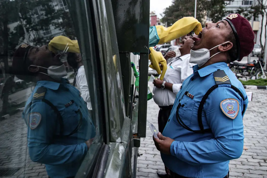 Nepal, Kathmandu: A health worker collects a swab sample from a policeman at a mobile coronavirus (COVID-19) testing vehicle. Photo: Prabin Ranabhat/dpa.
