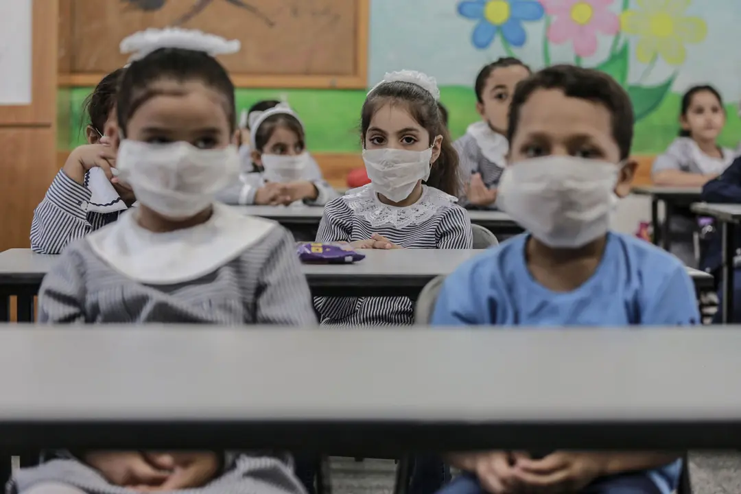 09 August 2020, Palestinian Territories, Al-Shati: Palestinian students sit inside a classroom at a school run by the United Nations Relief and Works Agency for Palestine Refugees (UNRWA) at Al-Shati refugee camp on the first day of the new school year amid concerns regarding the spread of the coronavirus (Covid-19) after almost five months since schools were shut down due to the ongoing pandemic. Photo: Mohammed Talatene/dpa.