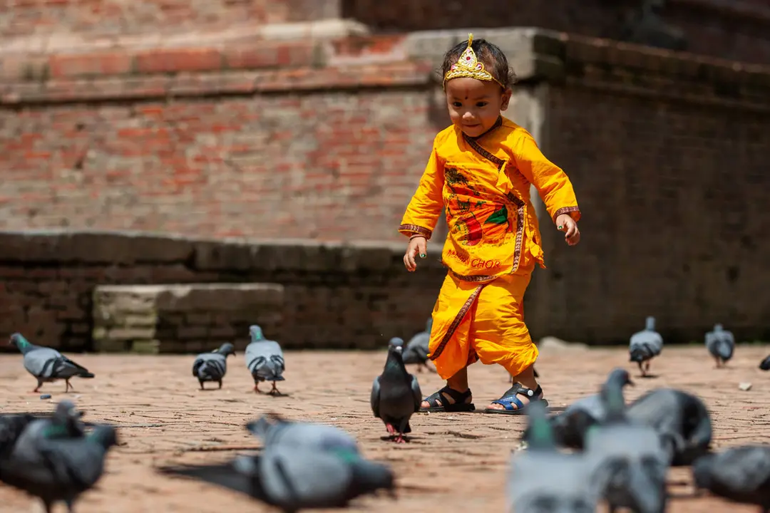11 August 2020, Nepal, Lalitpur: A boy dressed as Krishna plays at the premises of Krishna Mandir during the Krishna Janmashtami festival at Patan Durbar Square. Photo: Prabin Ranabhat/dpa.