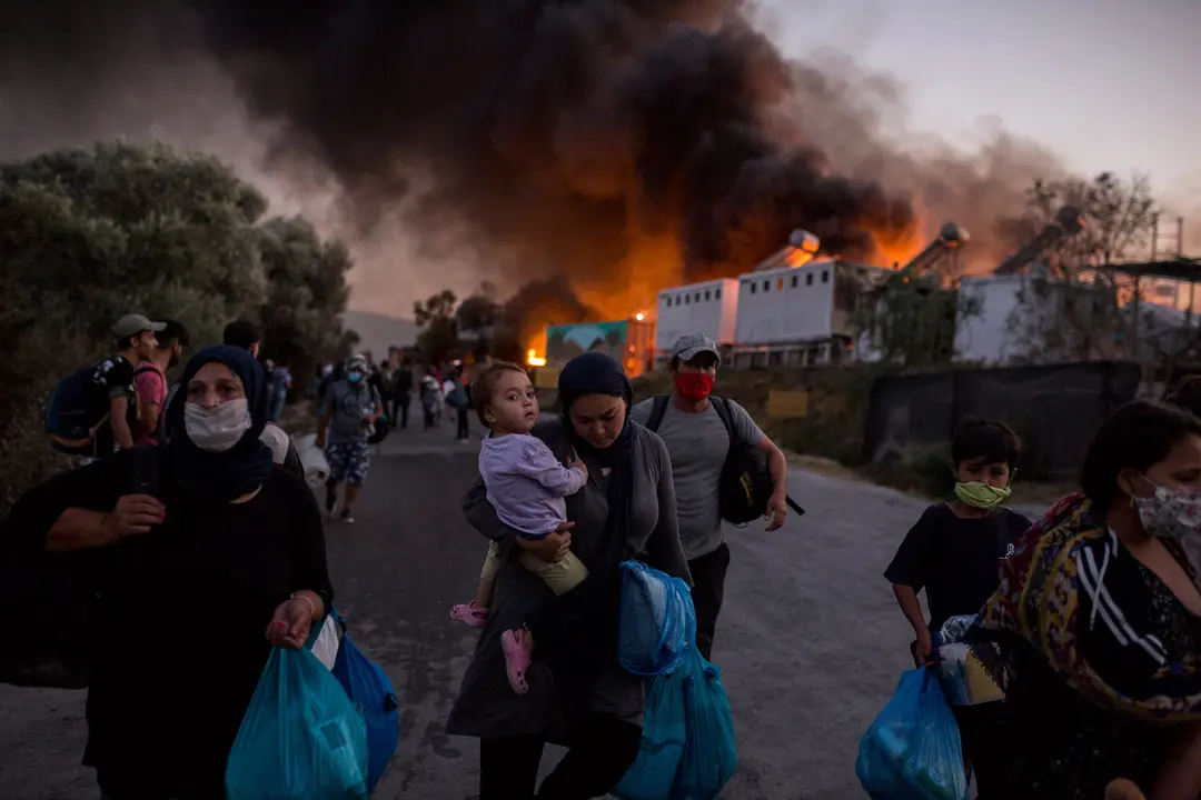09 September 2020, Greece, Moria: People carry their belongings as they flee from the Moria refugee camp after a major fire broke out in Greece&#39;s largest migrant camp leaving thousands of them homeless. Photo: Socrates Baltagiannis/dpa.