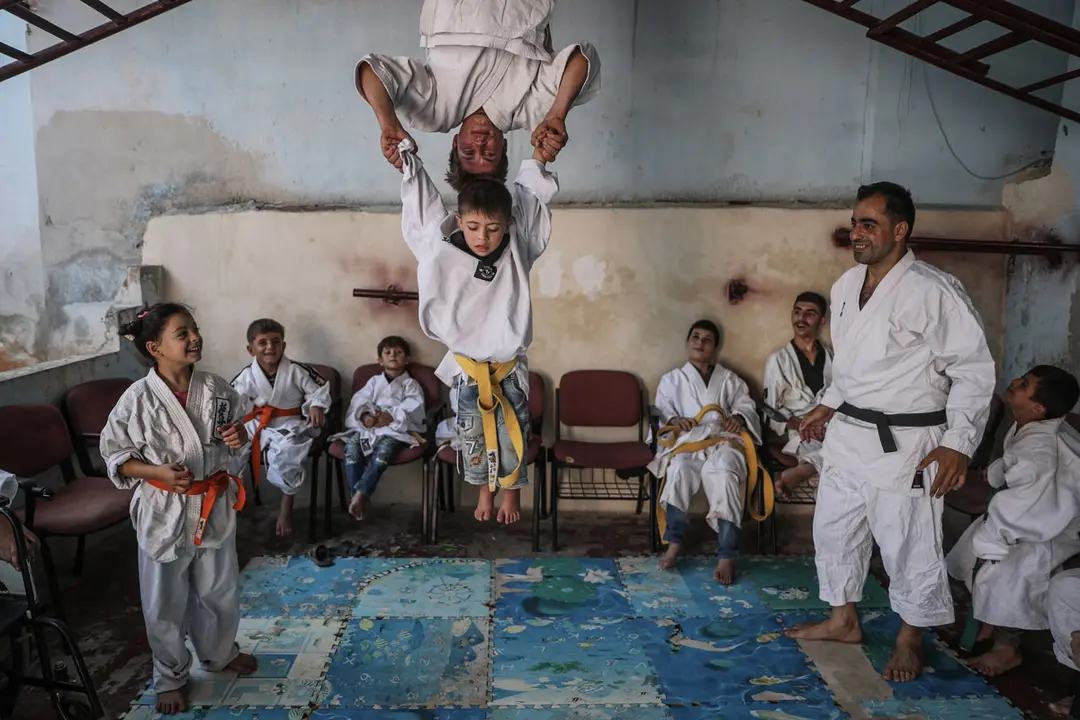 16 September 2020, Syria, Aleppo: Wasim Satot, 38 years-old, a karate coach holding a black belt, trains children during a Karate training class inside a school owned by his mother for special needs children such as Down’s syndrome, Autism and other disabilities, in Aljiina village in Aleppo countryside. Wasim is a physical education teacher began his own karate project year ago, in which he was keen to merge between 10 special needs children and other 10 healthy children in age between 6 and 15 into a karate training class to integrate them together into society through sport. Photo: Anas Alkharboutli/dpa.