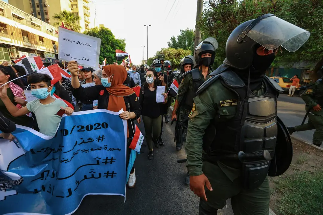 01 October 2020, Iraq, Baghdad: Police personnel accompany demonstrators marching from Firdos Square to Tahrir square, during a rally to mark the first anniversary of October&#39;s anti-government demonstrations in Iraq. Photo: Ameer Al Mohammedaw/dpa.