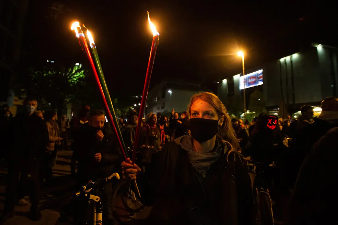 02 October 2020, Slovenia, Ljubljana: A protester wearing a face mask carries torches during an anti-government protest. Photo: Luka Dakskobler/dpa.