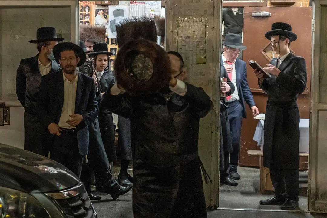 10 October 2020, US, New York: An Orthodox Jewish man hides his face from the camera during a prayer gathering on the Jewish holiday of Simchat Torah at the Borough Park neighbourhood of Brooklyn. New York Governor Andrew Cuomo placed restrictions on gatherings at synagogues and other houses of worship amid the spread of the coronavirus pandemic. Photo: Ron Adar/dpa.