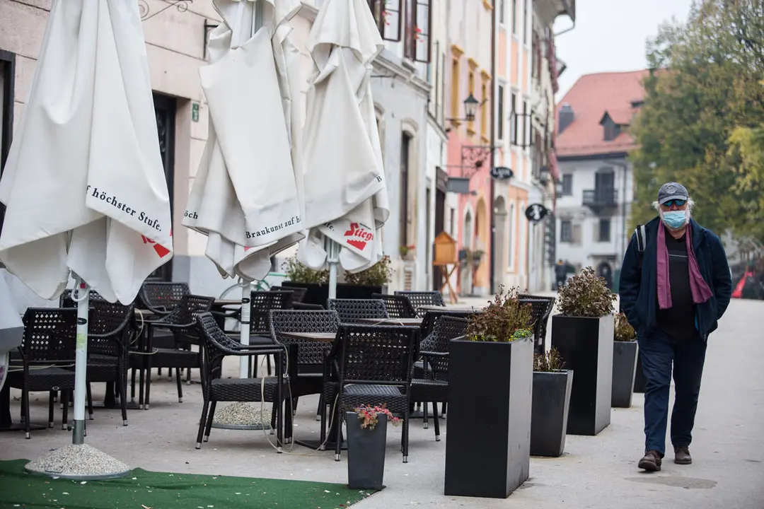 19 October 2020, Slovenia, Skofja Loka: A man wears a face mask while he walks by a closed bar terrace as the Slovenia government decides to introduce an overnight curfew in order to curb the spreading of the coronavirus. Photo: Luka Dakskobler/dpa.