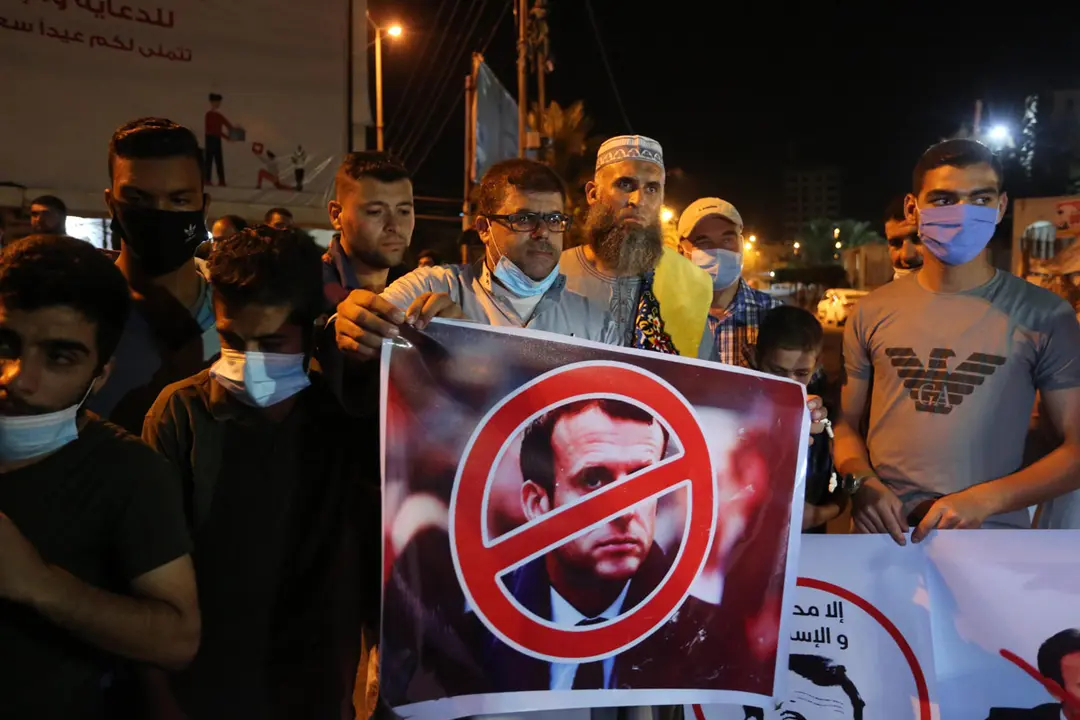 24 October 2020, Palestinian Territories, Khan Yunis: Palestinians hold anti-French President Emmanuel Macron poster during a protest against the insulting graffiti of the Islamic prophet Muhammad which was published in a French caricature magazine that has recently spread widely among the French. Photo: Ashraf Amra/dpa.