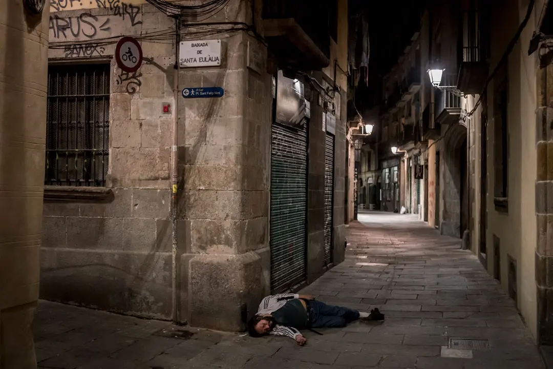 25 October 2020, Spain, Barcelona: A man lies on the ground at an empty street before the start of the curfew. Spain&#39;s government imposes an obligatory night-time curfew between 11 pm and 6 am for at least two weeks amid the spread of the coronavirus. Photo: Jordi Boixareu/dpa.