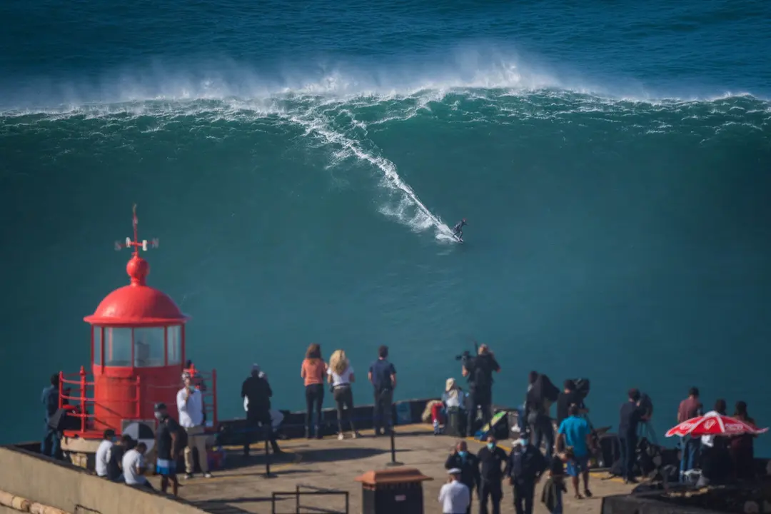 29 October 2020, Portugal, Nazare: People watch German surfer Sebastian Steudtner rides a wave during a tow surfing session at Praia do Norte beach at the beginning of the winter season. Photo: Henrique Casinhas/dpa.