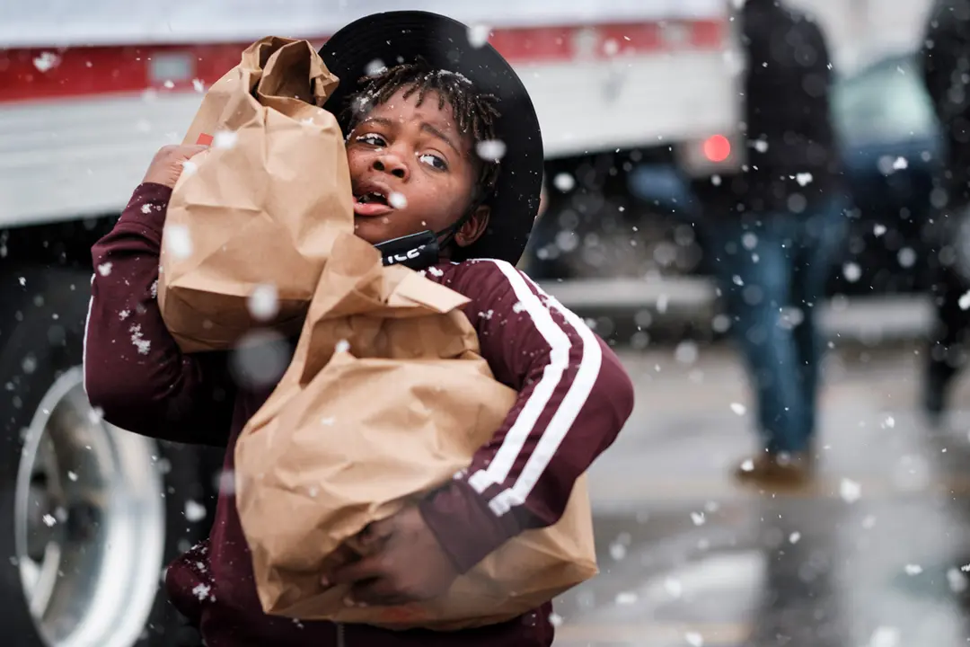 23 November 2020, US, Des Moines: A volunteer child carries bags of food during a Thanksgiving food distribution event organized by Urban Dreams, a community empowerment NGO. Photo: Jack Kurtz/ZUMA Wire/dpa.