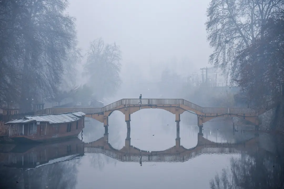 03 December 2020, India, Srinagar: A man walks on a wooden bridge during a cold foggy morning. Photo: Idrees Abbas/SOPA Images via ZUMA Wire/dpa