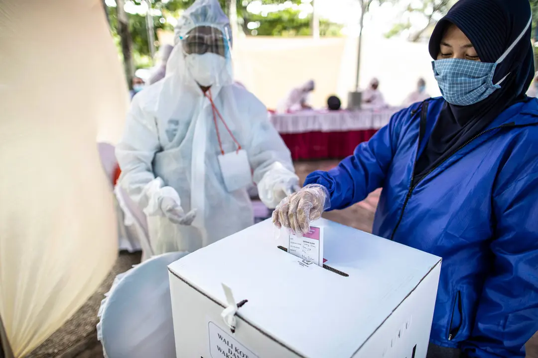 09 December 2020, Indonesia, South Tangerang: A woman casts her ballot at a polling station during the Indonesian local elections 2020 amid the spread of the coronavirus. Photo: Donal Husni/ZUMA Wire/dpa