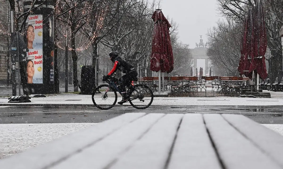 03 January 2021, Berlin: A cyclist rides through the snow at the Brandenburg Gate. Photo: Britta Pedersen/dpa