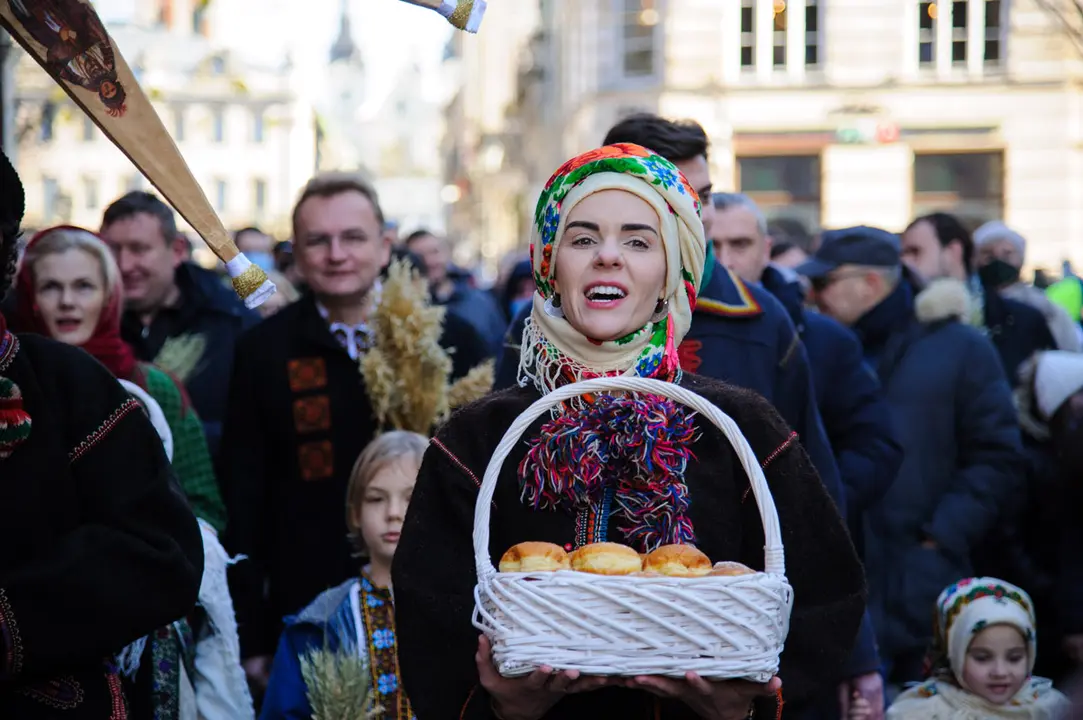 06 January 2021, Ukraine, Lviv: An Ukrainian woman sings while carrying a basket of buns during the Orthodox Christmas Day parade in downtown Lviv. Photo: Mykola Tys/SOPA Images via ZUMA Wire/dpa