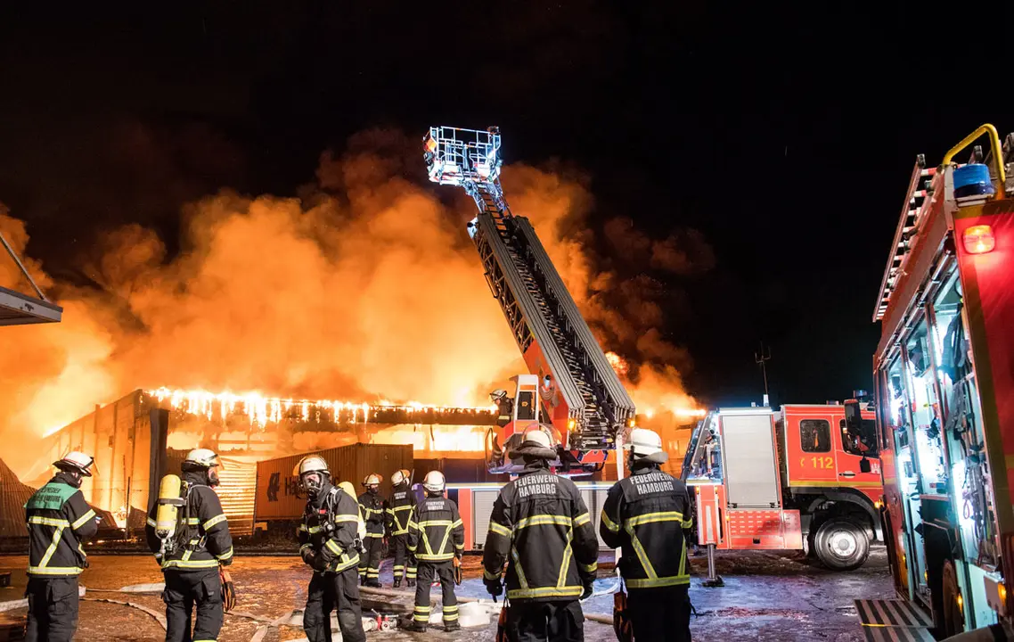 13 January 2021, Hamburg: Firefighters work to extinguish a fire in a warehouse in the Wilhelmsburg district. Photo: Daniel Bockwoldt/dpa