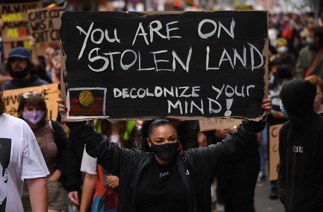 26 January 2021, Australia, Melbourne: A protester holds a placard during an Invasion Day rally. Indigenous Australians refer to Australia Day, which is commemorating the arrival of the First British Fleet to Sydney in 1788, as 'Invasion Day' and there is growing support to change the date to one which can be celebrated by all Australians. Photo: James Ross/AAP/dpa