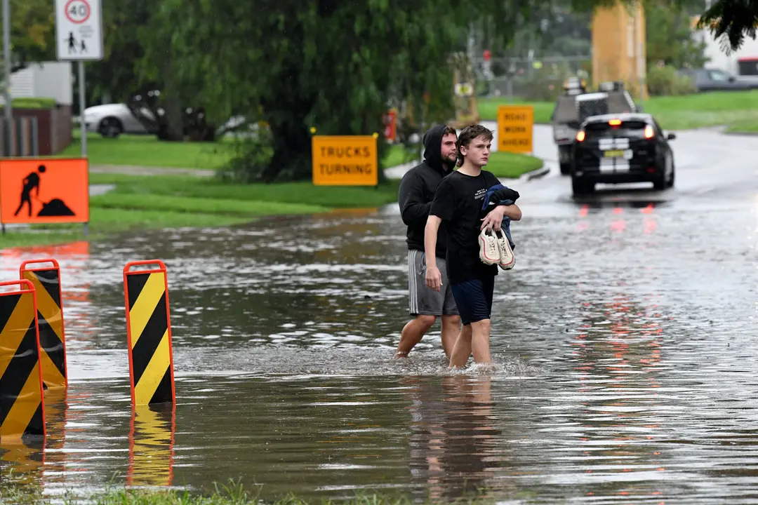 21 March 2021, Australia, Sydney: People walk through a submerged road amid floods sweeping across New South Wales as a result of heavy rains. Photo: Bianca De Marchi/AAP/dpa