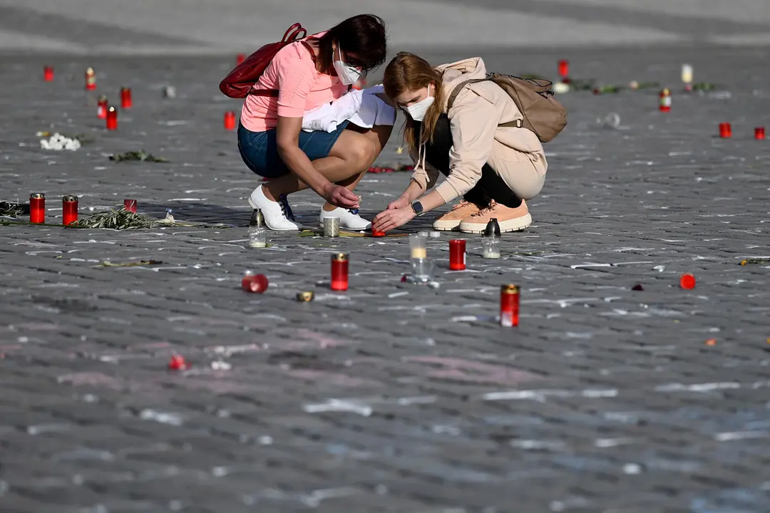 31 March 2021, Czech Republic, Prague: Women light candles at the crosses painted on the Old Town Square pavement, which has become an improvised Memorial site for COVID-19 victims. Photo: Deml Ond&oslash;ej/CTK/dpa