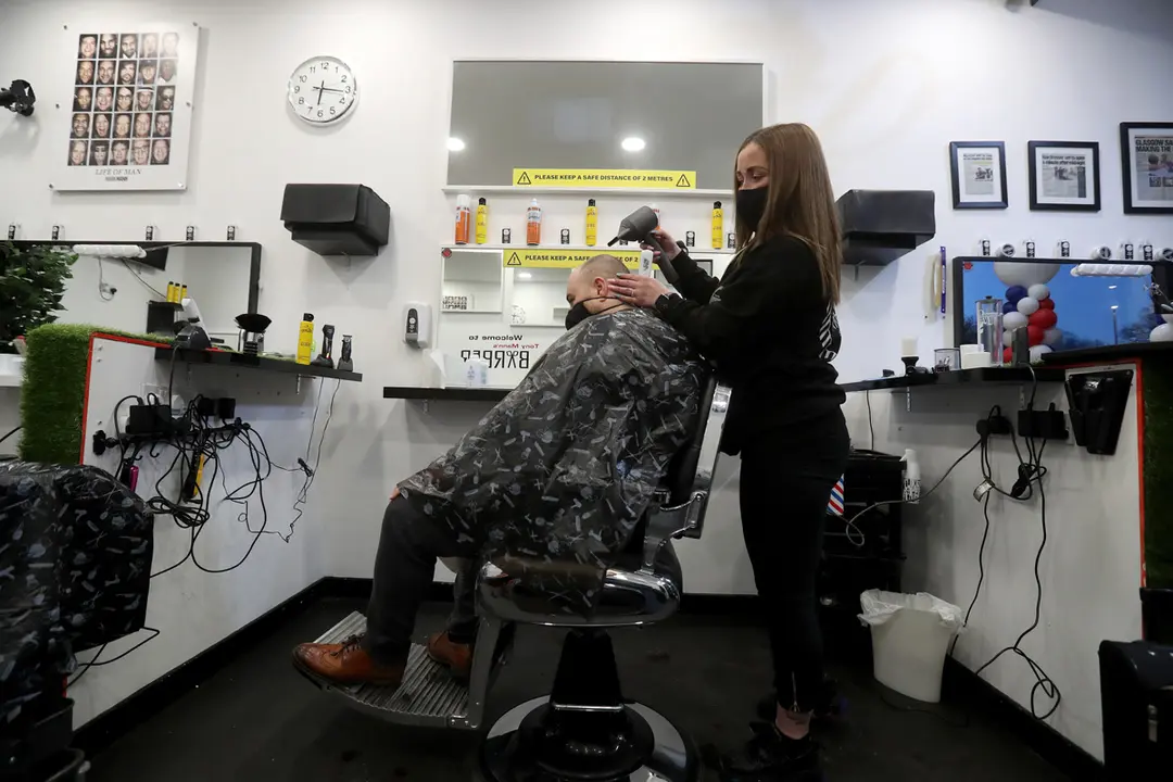05 April 2021, United Kingdom, Giffnock: Barber Maggie McGillivray trims Sam Rosenblom's hair at Tony Mann's Barber Shop in Giffnock near Glasgow as barbers reopen across Scotland. Photo: Andrew Milligan/PA Wire/dpa