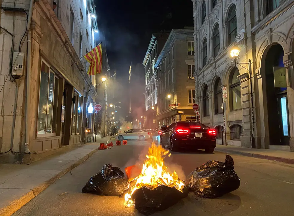 11 April 2021, Canada, Montreal: People burn rubbish bags during a protest in Old Montreal against a new curfew starting at 8pm to curb the spread of the coronavirus pandemic. Photo: Giuseppe Valiante/The Canadian Press via ZUMA/dpa