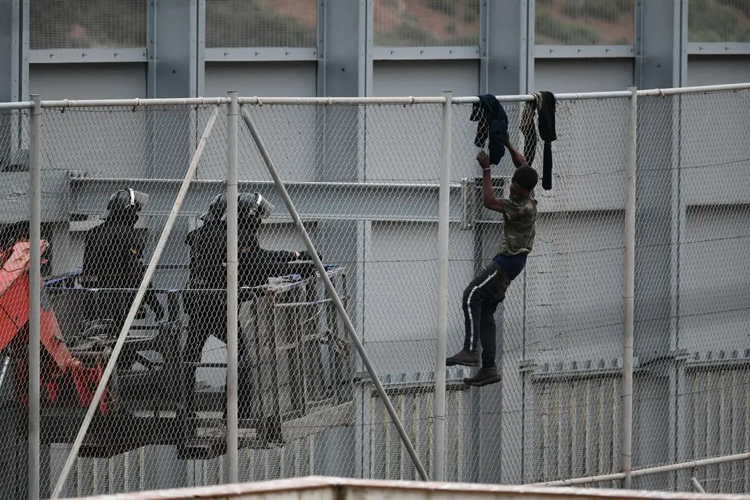 Police officers approach a migrant trying to jump the fence that separates Ceuta in Spain from Morocco. In the early hours of Tuesday, 13 April, a group of at least 60 migrants tried to jump the border fence to enter Spanish territory. Photo: Antonio Sempere/EUROPA PRESS/dp