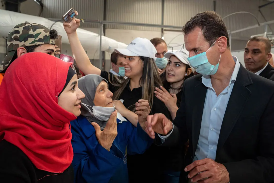 HANDOUT - 03 May 2021, Syria, Hassia: A photo released by the Syrian official news agency SANA on 03 May 2021 shows Syrian President Bashar Al-Assad speaking with workers during his visit to several facilities and factories in Hassia Industrial City. Photo: -/SANA/dpa - ATTENTION: editorial use only and only if the credit mentioned above is referenced in full