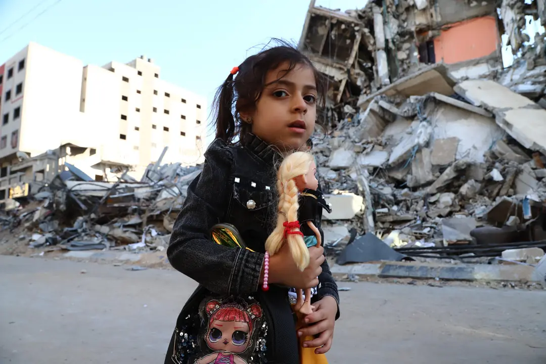 13 May 2021, Palestinian Territories, Gaza City: A girl walks past houses destroyed after an Israeli airstrike on Gaza City amid the escalating flare-up of Israeli-Palestinian violence. Photo: Naaman Omar/APA Images via ZUMA Wire/dpa