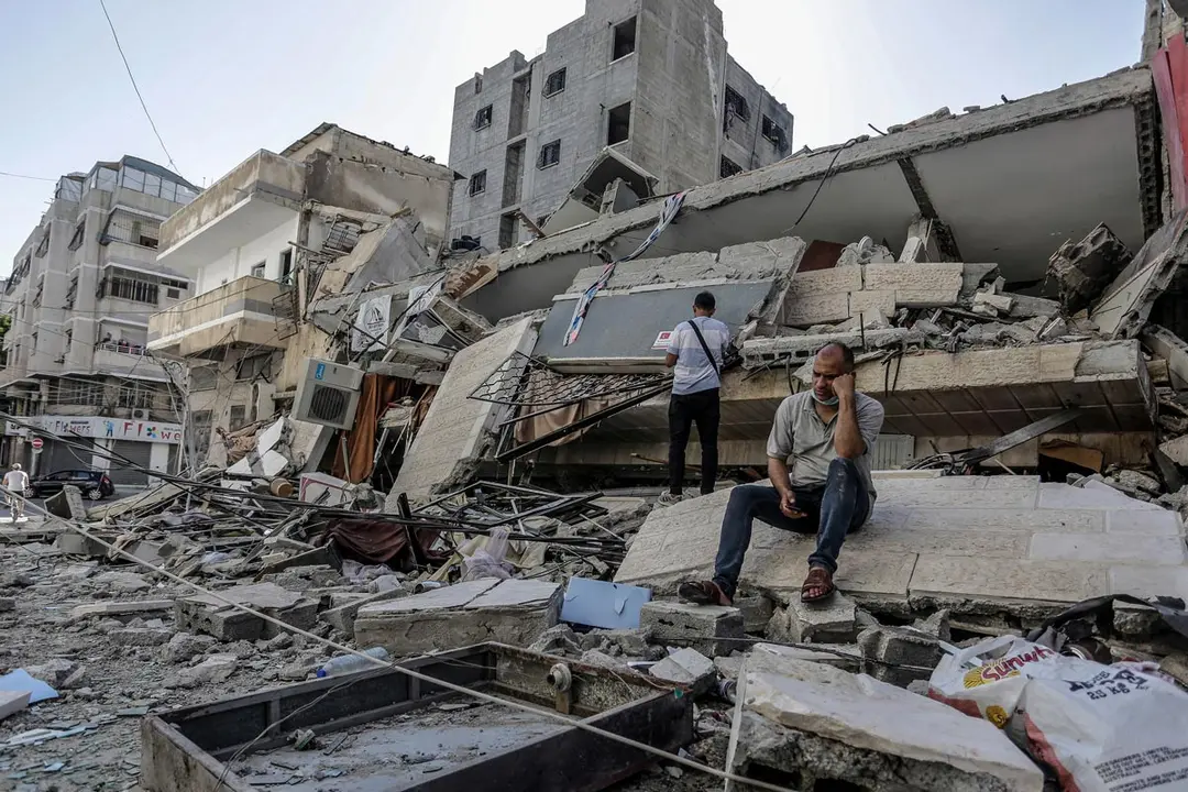 14 May 2021, Palestinian Territories, Gaza City: A Palestinian man sits on the remains of his destroyed family house after it was hit by Israeli airstrikes, amid the escalating flare-up of Israeli-Palestinian violence. Photo: Mahmoud Issa/SOPA Images via ZUMA Wire/dpa