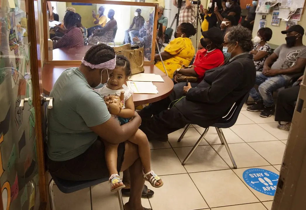 24 May 2021, US, Miami: Julie Jean (L), an undocumented immigrant from Haiti, holds her 2-year-old daughter, Maria J. Tellez while listening to a press conference regarding the Biden administration's redesignation of Temporary Protected Status (TPS) for Haitians. Julie arrived in Miami in 2016, leaving behind her son in Haiti and said that she is hopeful to be able to get papers to see her son and to bring him to Miami. The Family Action Network Movement (FANM) held a press conference at their office in Little Haiti neighbourhood in Miami to applaud the Biden administration's redesignation of TPS for Haitians that was announced on Saturday, 22 May 2021. Photo: Emily Michot/TNS via ZUMA Wire/dpa