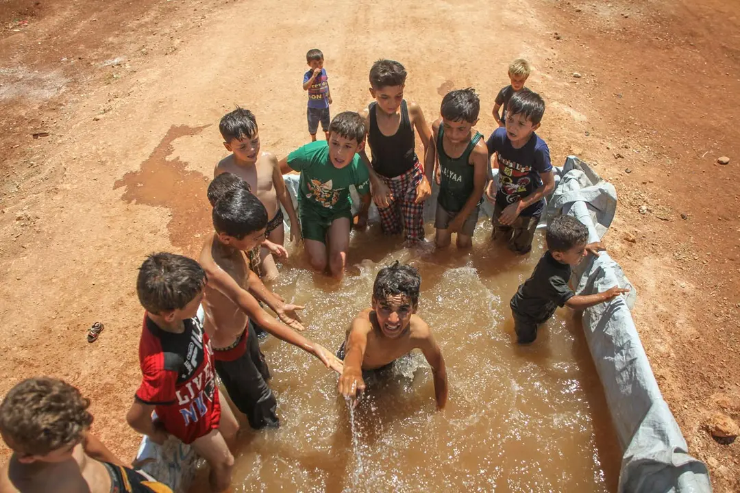 05 June 2021, Syria, Idlib: Displaced children in the northern Idlib camp swim inside the back of a truck to cool off from high temperatures. Photo: Moawia Atrash/ZUMA Wire/dpa