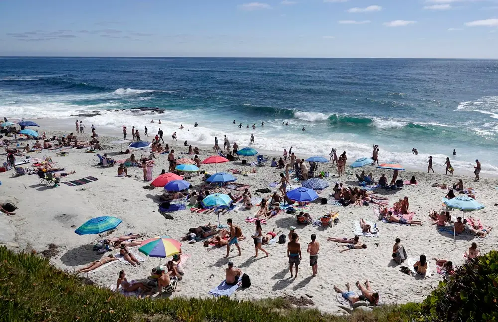 13 June 2021, US, San Diego: People pack the coast on a warm afternoon at Windansea Beach in La Jolla. After a 15-months of public health restrictions, mandates, and color-coded tiers to stem the COVID-19 pandemic, the state of California will fully reopen On 15 June. Photo: K.C. Alfred/ZUMA Wire/dpa
