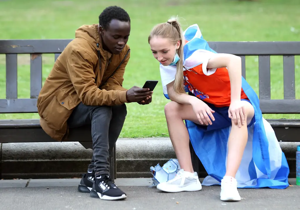 18 June 2021, United Kingdom, Glasgow: Scotland fans watch the UEFA EURO 2020 Group D soccer match between England and Scotland on a smartphone. Photo: Robert Perry/PA Wire/dpa.