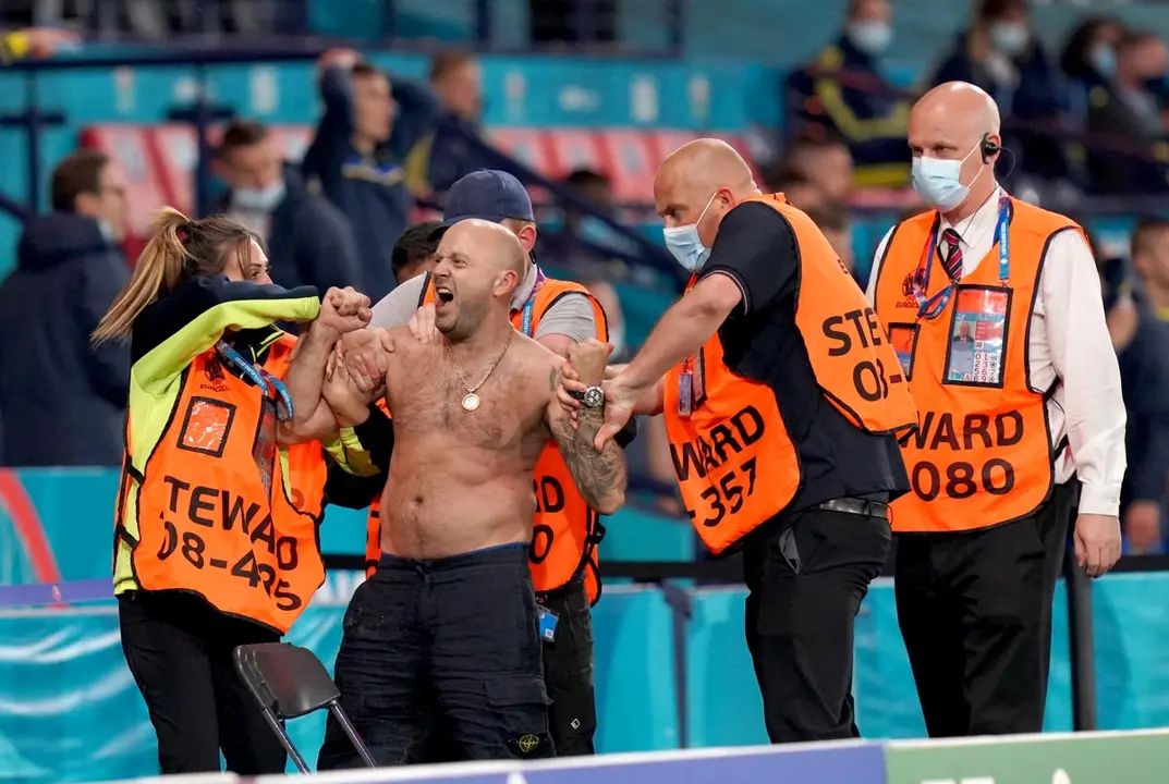 29 June 2021, United Kingdom, Glasgow: A pitch invader is removed by security during the UEFA EURO 2020 round of 16 soccer match between Sweden and Ukraine at Hampden Park. Photo: Jane Barlow/PA Wire/dpa