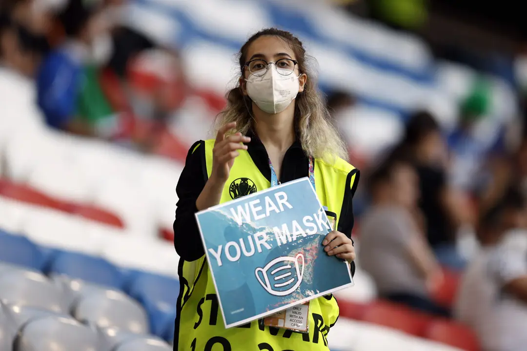 02 July 2021, Munich: A steward holds a poster reading "wear your mask" ahead of the UEFA EURO 2020 quarter-final soccer match between Italy and Belgium at the Allianz Arena. Photo: Bruno Fahy/BELGA/dpa
