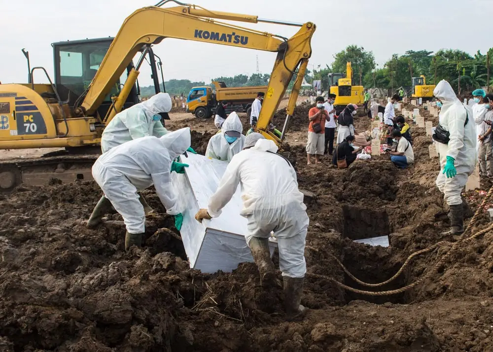 08 July 2021, Indonesia, East Jakarta: Undertakers wearing Personal Protective Equipment suits (PPE) bury the coffin of a covid-19 victim at Rorotan public cemetery. Indonesia on Thursday reported a new daily record of 38,391 coronavirus infections, plus 852 new fatalities. Photo: Agung Fatma Putra/SOPA Images via ZUMA Wire/dpa