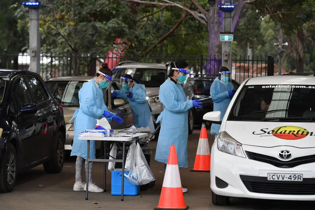 14 July 2021, Australia, Sydney: Health workers wearing protective suits collect swab samples at a pop up COVID-19 testing clinic at the Fairfield Showgrounds. Long queues are forming around the pop up COVID-19 clinic at the Fairfield Showgrounds. Photo: Mick Tsikas/AAP/dpa