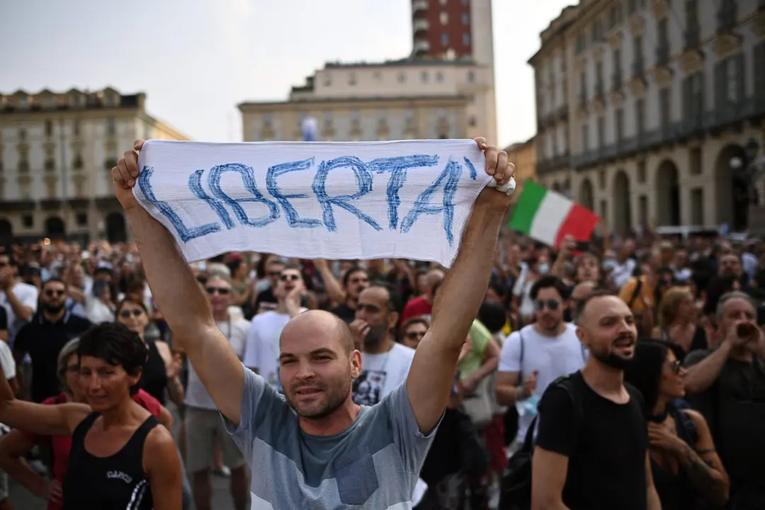 24 July 2021, Italy, Turin: A man holds a sign during a demonstration against the green pass and against the so-called "health dictatorship", after the Italian government decided that from August 6 it will be mandatory to issue the pass after the first dose of vaccine for access to sporting events, fairs, conferences, museums, theme parks and amusement parks, spas, bingo halls and casinos, theaters, cinemas, concerts, public competitions, to sit at the tables of indoor bars and restaurants and swimming pools, gyms indoors. Photo: Marco Alpozzi/LaPresse via ZUMA Press/dpa