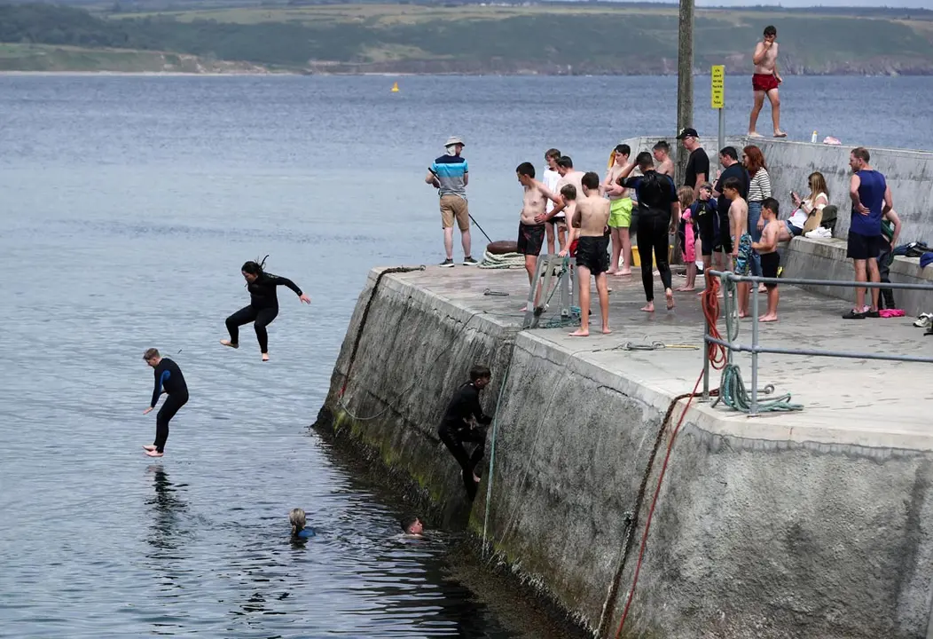 04 August 2021, Ireland, County Waterford: People jump in water at Ardmore beach in County Waterford. Photo: Niall Carson/PA Wire/dpa
