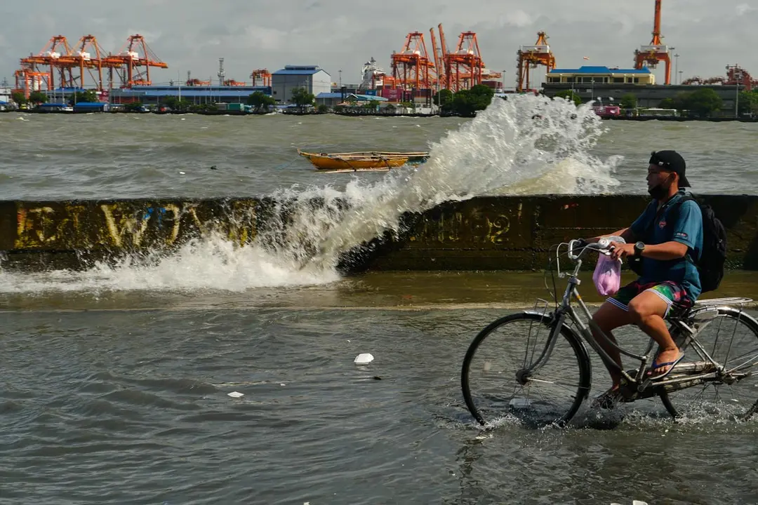 07 August 2021, Philippines, Manila: A man rides his bicycle through a flooded street at the BASECO compound. Due to the Monsoon winds, ocean waves flood the side streets of the BASECO compound in Manila. Photo: George Buid/ZUMA Press Wire/dpa