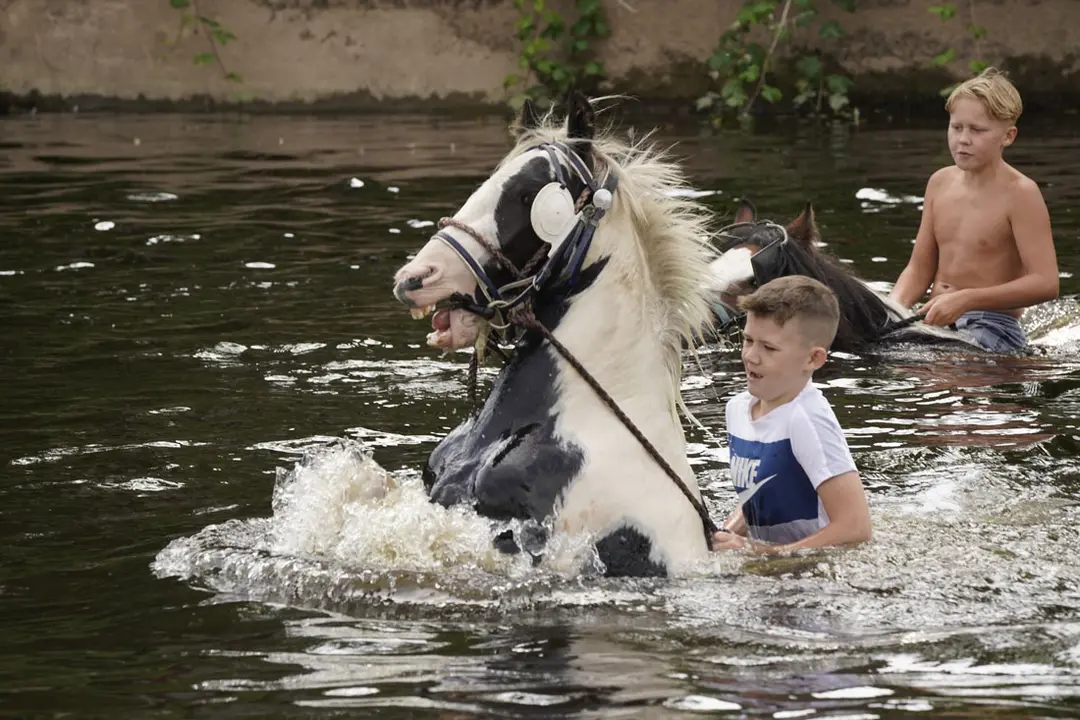 12 August 2021, United Kingdom, Appleby: Children ride horses at the River Eden during the annual Appleby Horse Fair. Photo: Owen Humphreys/PA Wire/dpa