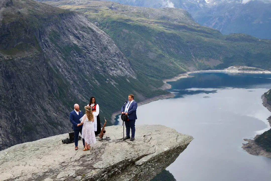 14 August 2021, Norway, Ullensvang: Kasper Sorensen (L) and Tinna Bundgaard Frentz are the first bride and groom to be married on the famous tourist rock formation "Trolltunga" in the presence of the Mayor of Ullensvang Roald Aga Haug (R) and Sarah Melkeraaen responsible for the musical elements during the wedding ceremony. Photo: Åse Marie Evjen / Trolltunga As/NTB/dpa