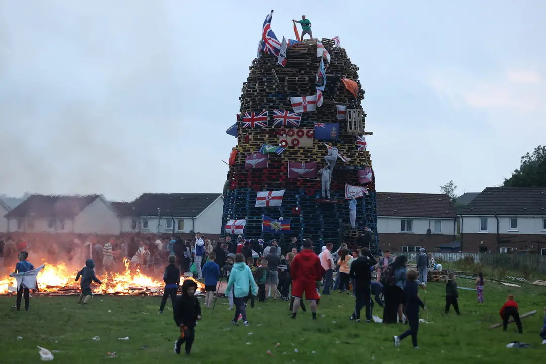 15 August 2021, United Kingdom, Londonderry: Flags are hung on a large bonfire being built to mark the Catholic Feast of the Assumption in the Bogside area of Londonderry. Photo: Liam Mcburney/PA Wire/dpa