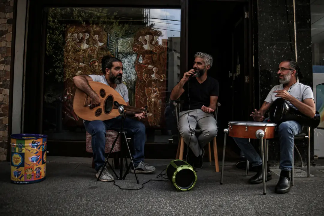 24 September 2021, Lebanon, Beirut: A group of Lebanese sing at a street pavement outside their shop during an electricity outage. Photo: Marwan Naamani/dpa