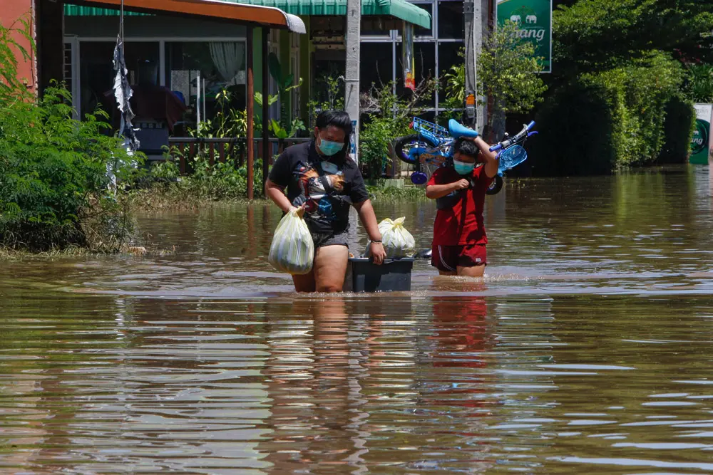 29 September 2021, Thailand, Lopburi: Residents carrying their belongings wade through floodwaters as Pasak Jolasid Dam overflows after tropical storm Dianmu hits the area. Photo: Chaiwat Subprasom/SOPA Images via ZUMA Press Wire/dpa
