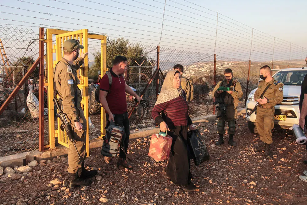 10 October 2021, Palestinian Territories, Salfit: Israeli soldiers are seen guarding the gate of the separation fence as Palestinian farmers make their way to pick olives outside the West Bank city of Salfit, near the Jewish settlement of Ariel. Photo: Nasser Ishtayeh/SOPA Images via ZUMA Press Wire/dpa