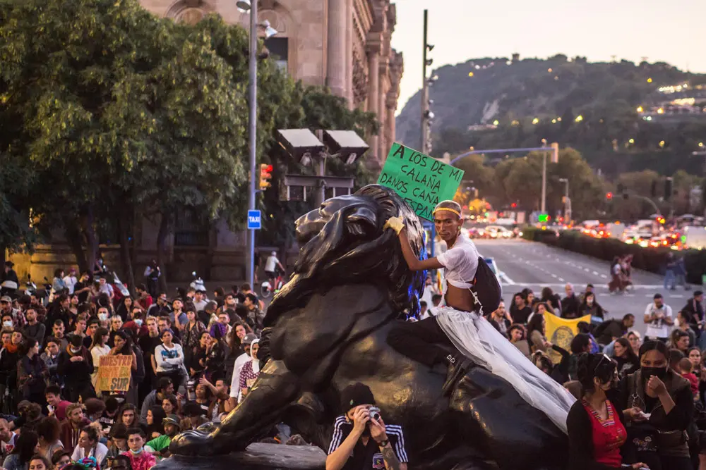 12 October 2021, Spain, Barcelona: A protester sits above one of the lions of the Christopher Columbus monument during a protest with the slogans "they will not conquer us" and "nothing to celebrate". Various anti-colonialist groups protest against the celebration of the National Day of Spain. Photo: Thiago Prudencio/SOPA Images via ZUMA Press Wire/dpa