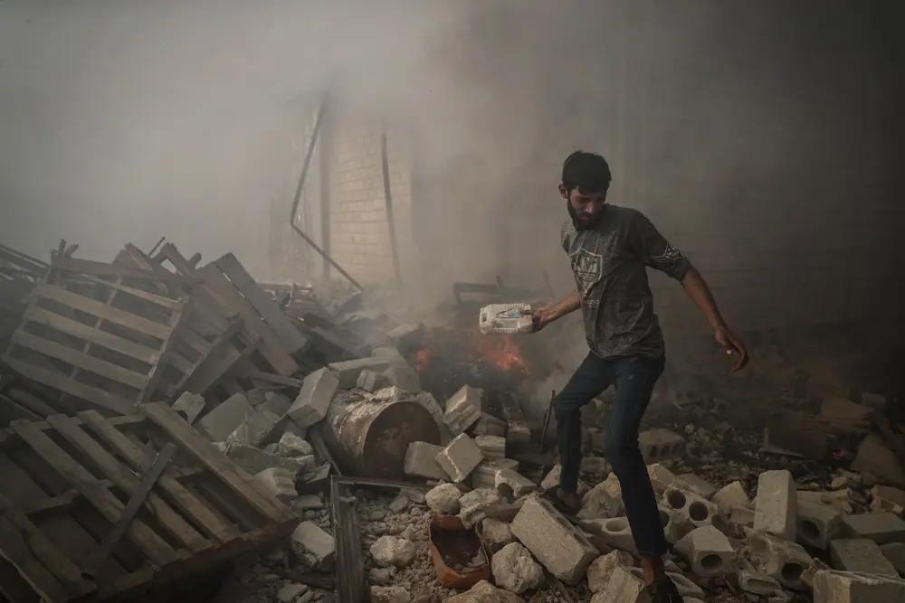 16 October 2021, Syria, Sarmada: A man tries to put out the fire in an industrial facility after it was targeted by missile shelling in the city of Sarmada, near the Bab Al-Hawa border crossing with Turkey. Today, 5 people were killed during the missile shelling that targeted different places near the Syrian-Turkish border Photo: Anas Alkharboutli/dpa